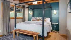 Une chambre à coucher avec un lit à baldaquin, un banc, une fenêtre avec des rideaux et un luminaire fixé au mur.