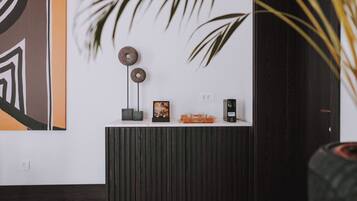 A reception desk with a modern design, featuring a wooden panel, a framed picture, a small plant, and a decorative item.