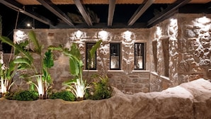 A stone building with large windows and a thatched roof. - Noir Mykonos (Mykonos)