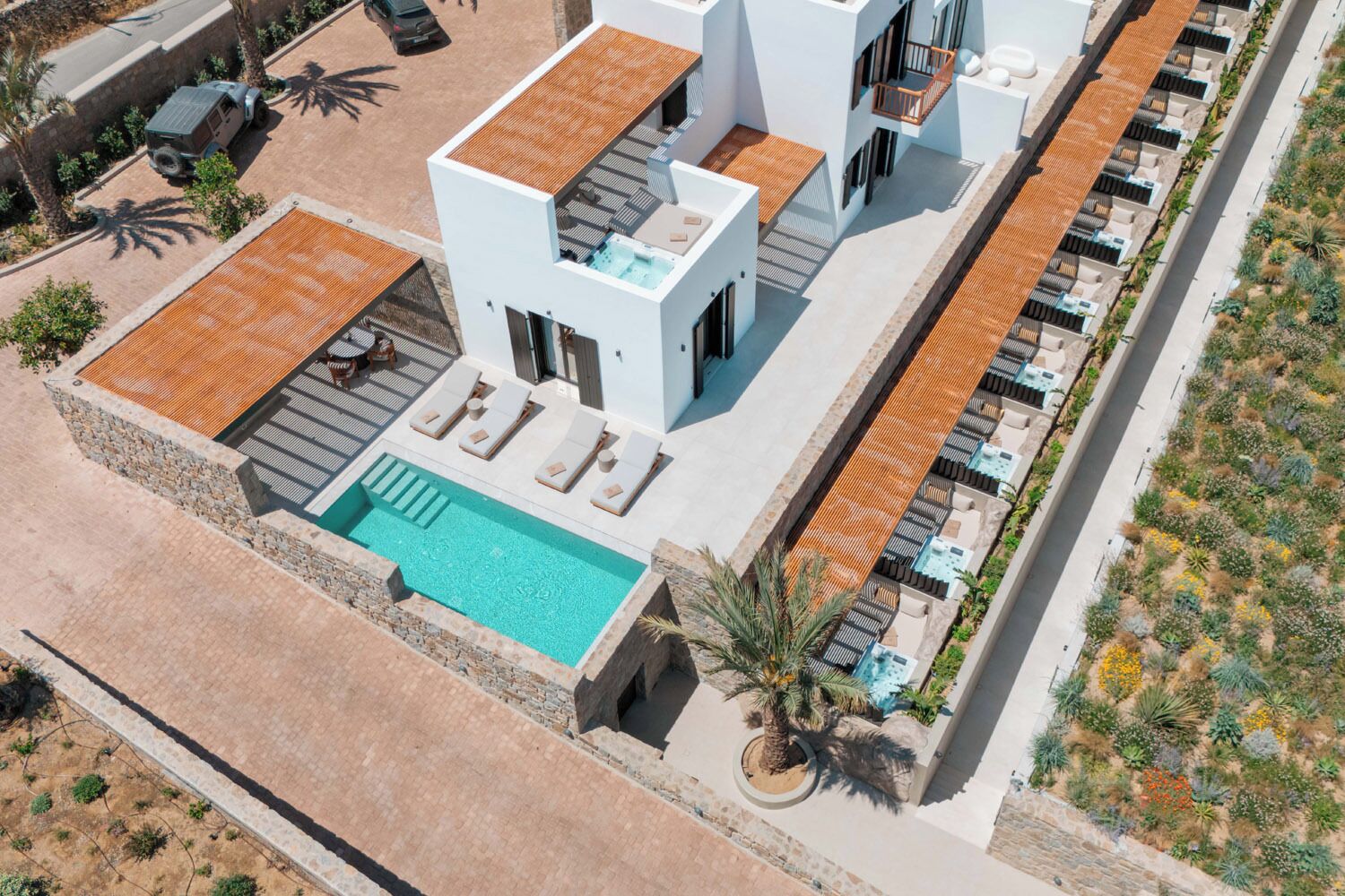 A modern hotel with a rooftop pool, outdoor seating, and a landscaped garden.