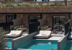 A modern outdoor pool area with built-in seating and a stone wall backdrop.