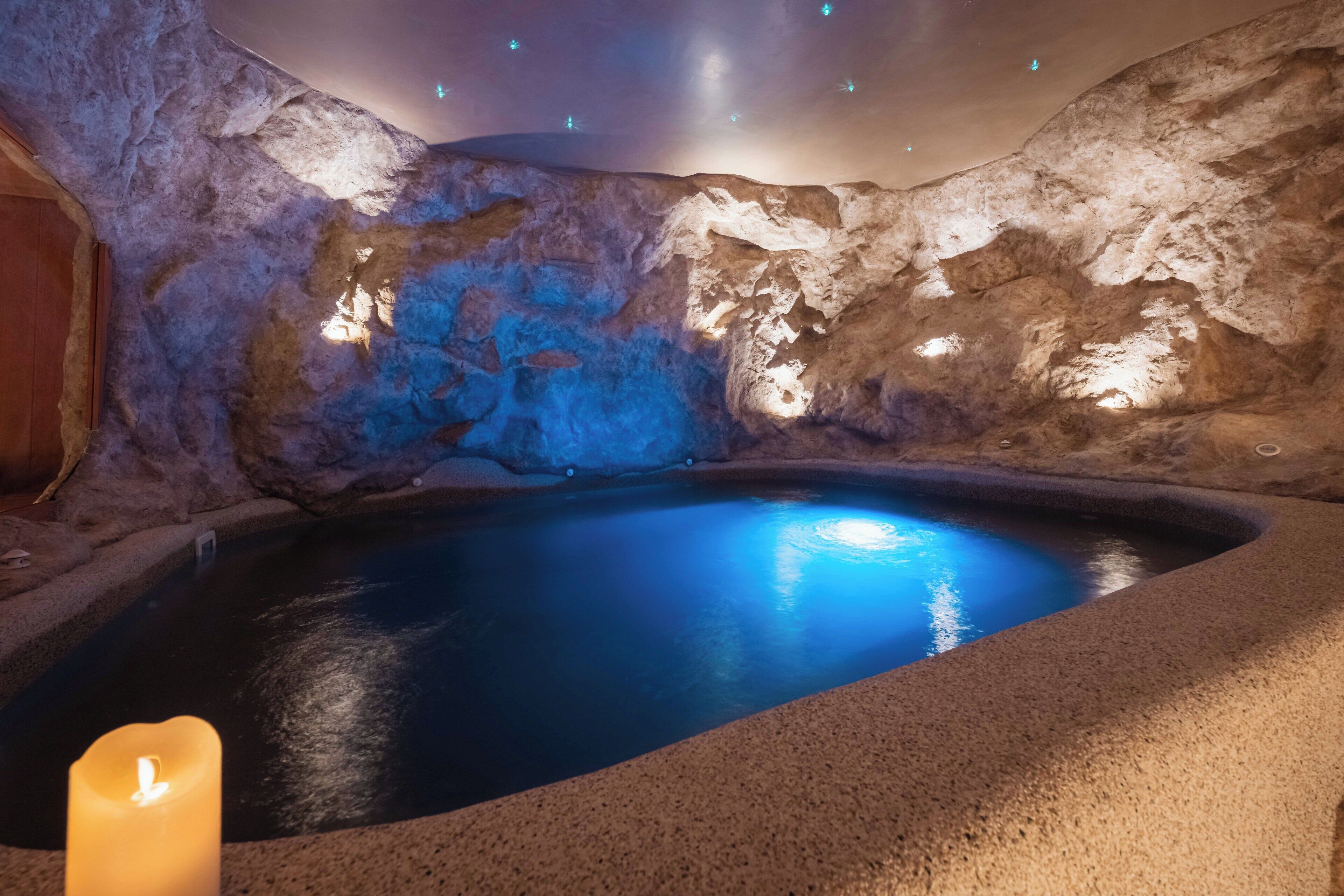A spa area with a hot tub, stone walls, and a candle.