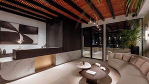 A modern interior with a marble reception desk, a curved sofa, and a round coffee table. - Noir Mykonos (Mykonos)