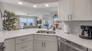 Una cocina moderna con armarios blancos, un lavamanos doble y una cafetera.