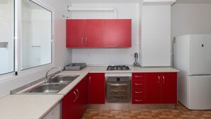 A kitchen with red cabinets, a white refrigerator, stainless steel appliances, and a window with a view. - CASA SALINAS - Apartment with mountain views and free wifi (Archidona)