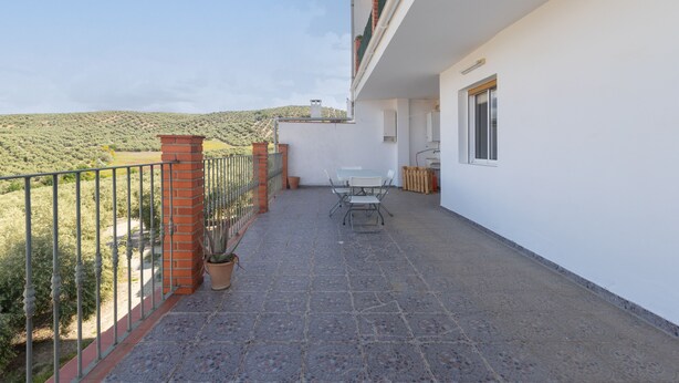 A balcony with a table and chairs, a potted plant, and a view of a hilly landscape. - CASA SALINAS - Apartment with mountain views and free wifi (Archidona)