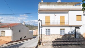 A two-story building with a white facade, stone base, and a tiled roof. - CASA SALINAS - Apartment with mountain views and free wifi (Archidona)