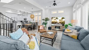 A spacious living room with a grey sofa, a coffee table, and a dining area with chairs and a table.