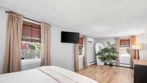 Une chambre à coucher avec un lit, une télévision, un bureau et une plante en pot.