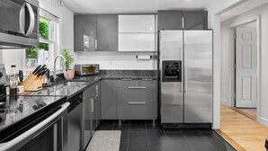 Une cuisine moderne équipée d’appareils électroménagers en acier inoxydable, d’un four encastré et d’un réfrigérateur.