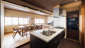 Une cuisine moderne dotée d’un îlot central, d’un coin repas avec une table et des chaises, et offrant une vue sur le salon.