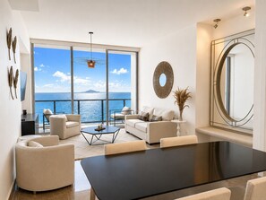 A modern living room with a large glass door leading to a balcony with a view of the sea. - Fantastic Apartment with Terrace in YOO (Ciudad de Panamá)