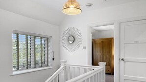 A staircase with white railings leading to a room with a large window and a decorative wall piece.