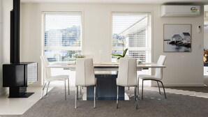 A modern dining area with a black wood-burning stove, a round table, and four white chairs.