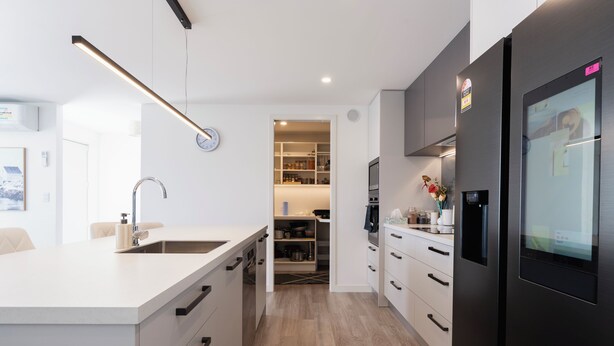 A modern kitchen with a central island, built-in appliances, and a walk-in pantry.