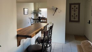 A dining area with a wooden table and chairs, a hanging light fixture, and a decorative wall piece. - Enjoy Gorgeous Mountain Views w/Privacy & Southwestern Ambiance Inside and Out! (Green Valley)