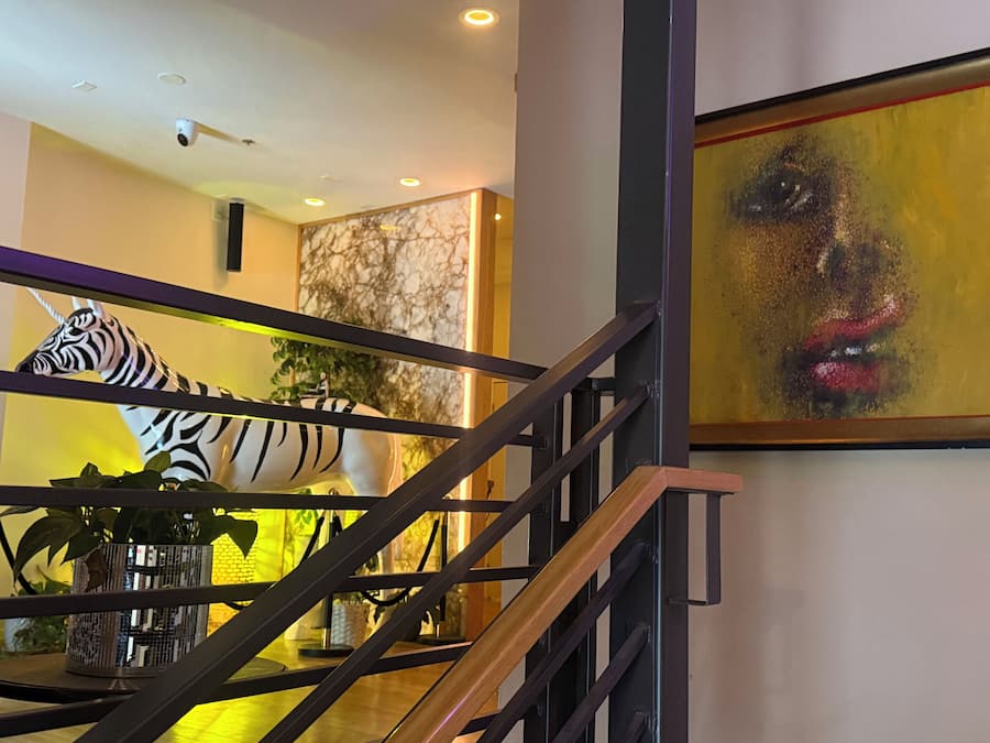 A staircase with a zebra sculpture, a painting, and a plant.