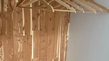 A wooden panel wall with a metal curtain rod and wooden hangers.