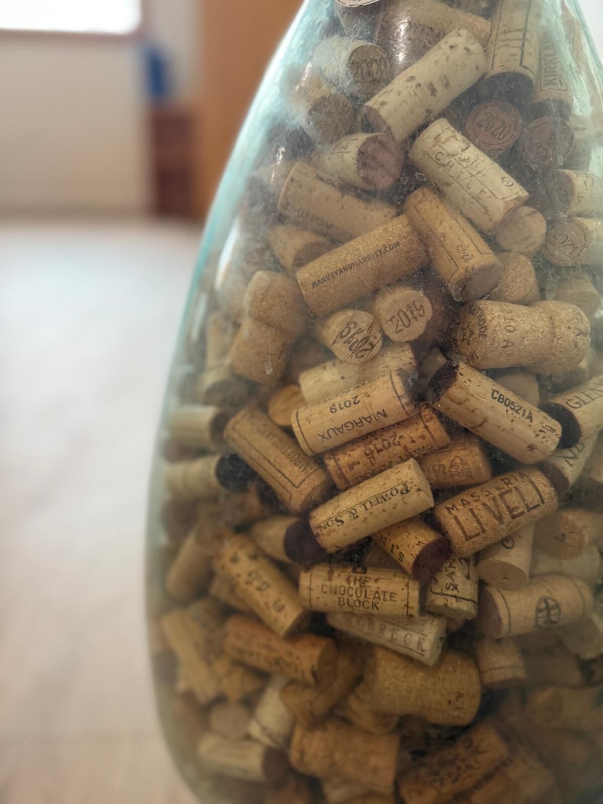 Una botella de vidrio transparente llena de numerosos tapones de vino.