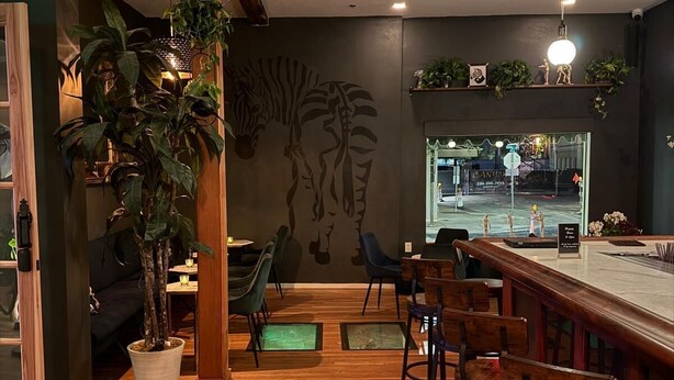 A restaurant with wooden flooring, bar seating, and a mural on the wall.