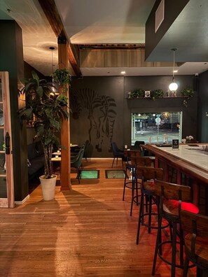 A restaurant with wooden flooring, bar seating, and a mural on the wall. - Unicorn Zebra (Tucson)