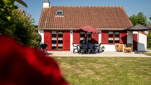 Une maison avec un toit recouvert de tuiles rouges, une petite fenêtre et un patio aménagé avec une table et des chaises.