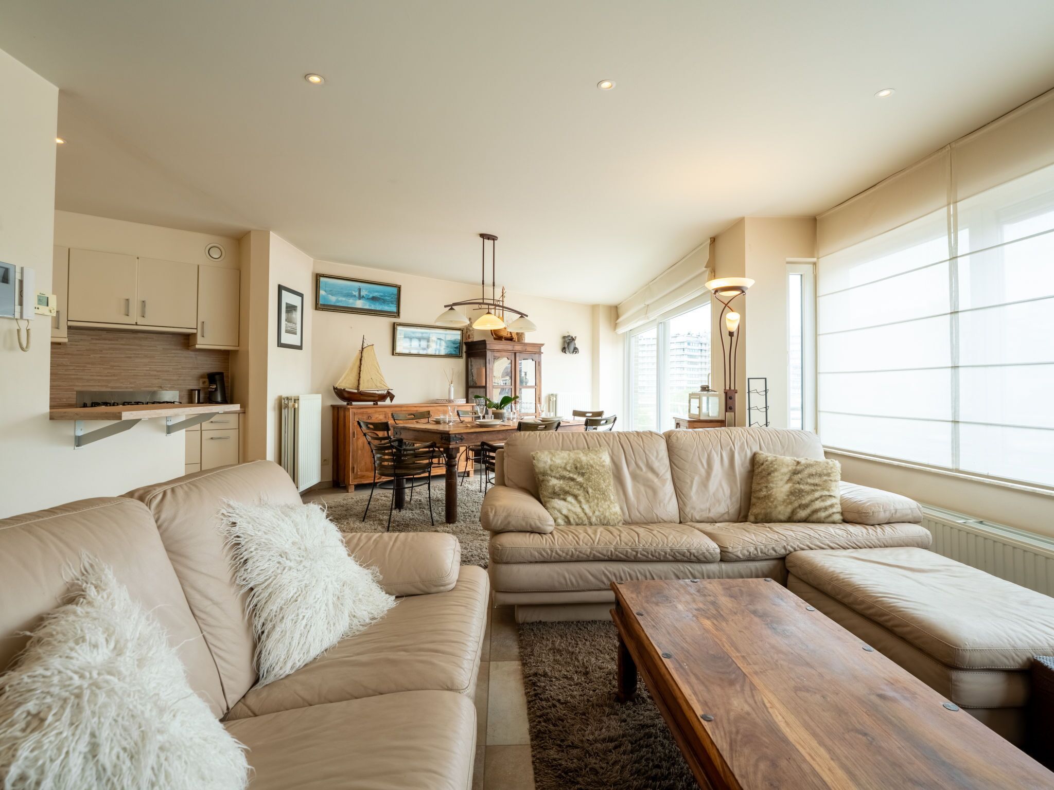A modern living room with a sofa, coffee table, and dining area.