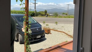 Eine Holzterrasse, im Hintergrund ist ein Auto geparkt.