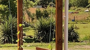 Eine Holzterrasse mit Blick auf einen angelegten Garten und eine Wiese.