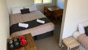 Ein Schlafzimmer mit einem Bett, einem Holztisch mit Weingläsern, einem Schreibtisch und einem Stuhl.