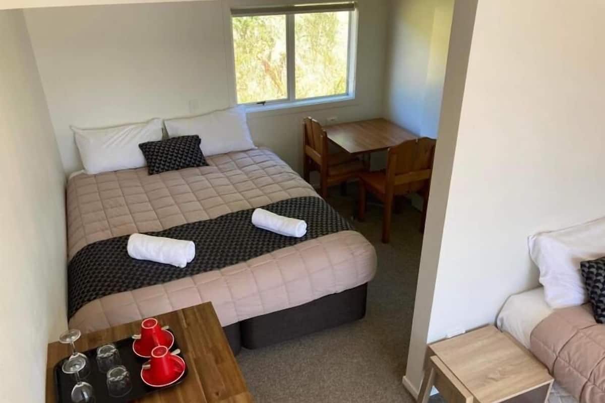 Une chambre à coucher avec un lit, une table en bois sur laquelle sont posés des verres à vin, un bureau et une chaise.