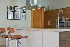Une cuisine moderne dotée d’un îlot central, d’appareils électroménagers en acier inoxydable et de meubles de rangement en bois.