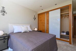 A bedroom with a bed, nightstands, a wardrobe, and a closet with hanging clothes. - Villa Puerto de Soller el Portet (Moraira)