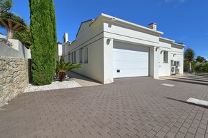 Una casa moderna con fachada blanca, un garaje y un camino de acceso pavimentado.