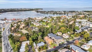 A coastal town with residential areas, a marina, and a road leading to the beach. - Retreat on Reid Street (Merimbula)