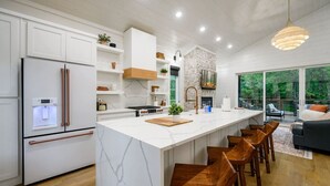 Una cocina moderna con una isla grande, armarios blancos y una pared decorativa de piedra.
