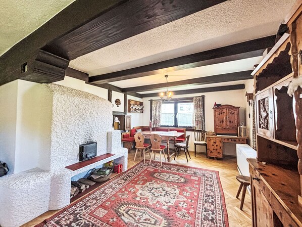 Un intérieur traditionnel avec une cheminée en pierre, des meubles en bois et un tapis rouge à motifs.