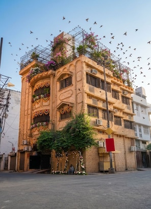 A multi-story building with balconies adorned with flowers and string lights. - Batra Guest House (Varanasi)