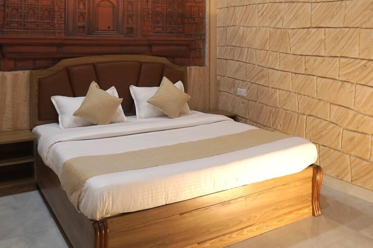 A bedroom with a bed, a mural of a historical building, and a stone wall.