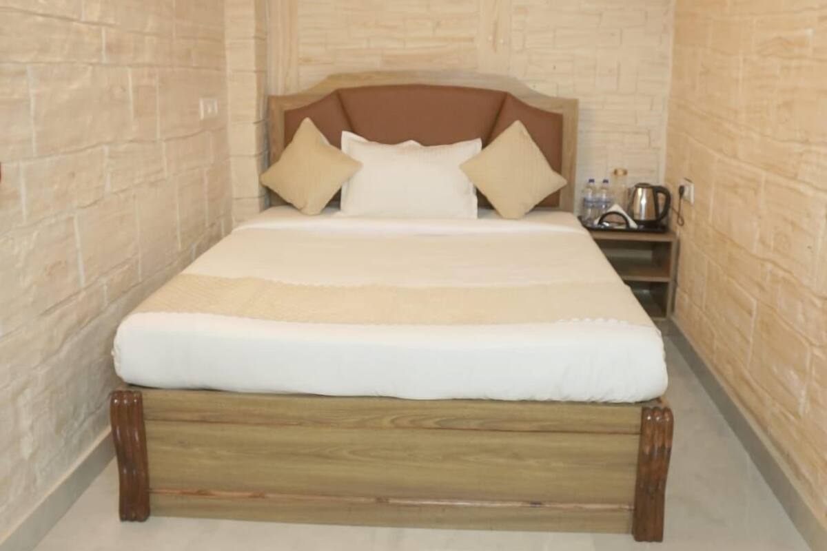 A bedroom with a wooden bed, a headboard, and a nightstand with a kettle.