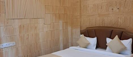 A wooden-paneled bedroom with a bed, pillows, and a small wooden nightstand.