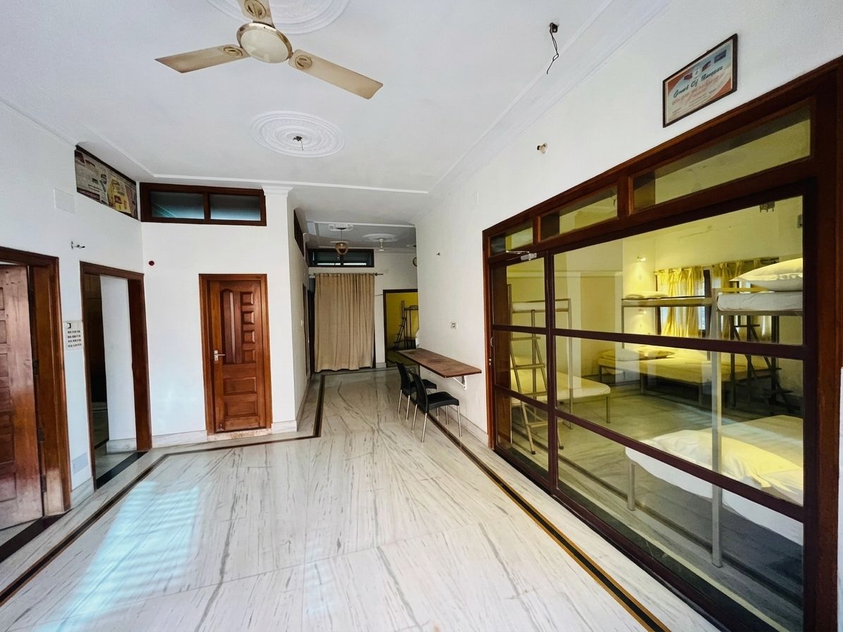 A hotel room with a large sliding glass door, a ceiling fan, and a wooden table with chairs.