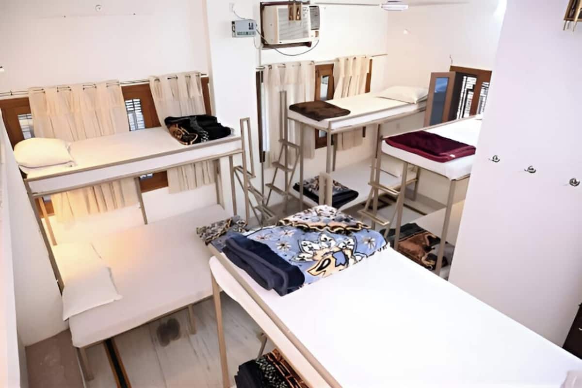 A dormitory room with bunk beds, a desk, and a chair.