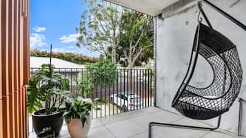 Enjoy a peaceful retreat on the balcony with a comfortable hanging chair and lush potted plants.