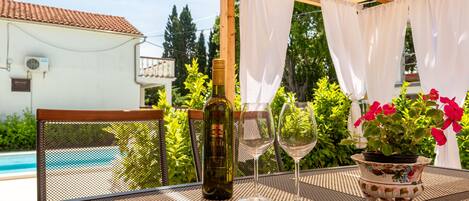 A patio with a table, a bottle of wine, and a glass.