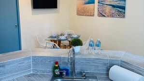 A modern kitchen with a built-in sink, a ceiling fan, and a flat-screen TV mounted on the wall.