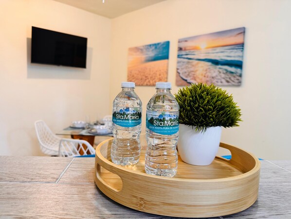 A wooden tray with two bottles of Sta. Maria water, a potted plant, and a dining area with a white chair and a table.