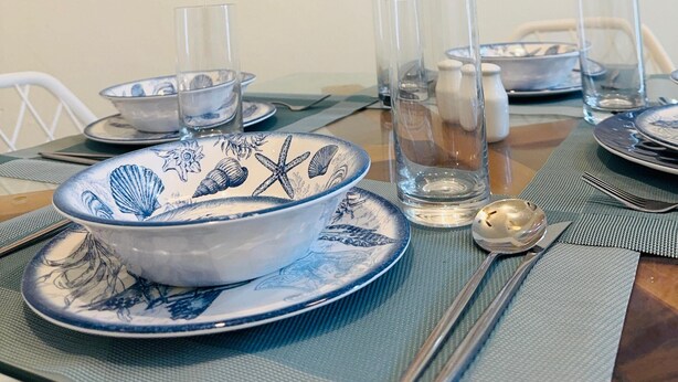 A dining table set with blue and white plates, clear glasses, and a spoon.