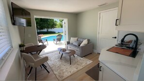 A compact living space with a dining area, a sofa, a small table, and a kitchen area with a built-in oven. - Poolside apartment in Port Orange (Port Orange)