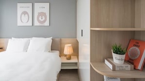 A modern bedroom with a bed, bedside table, lamp, and wall art. - Vinhomes D'Capital - SunhouseLand (Hanoi)